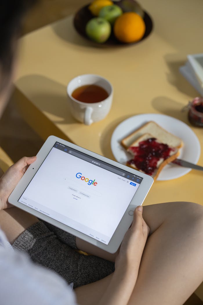 gallery-3 Person using a tablet with Google search open while having breakfast with toast and tea.